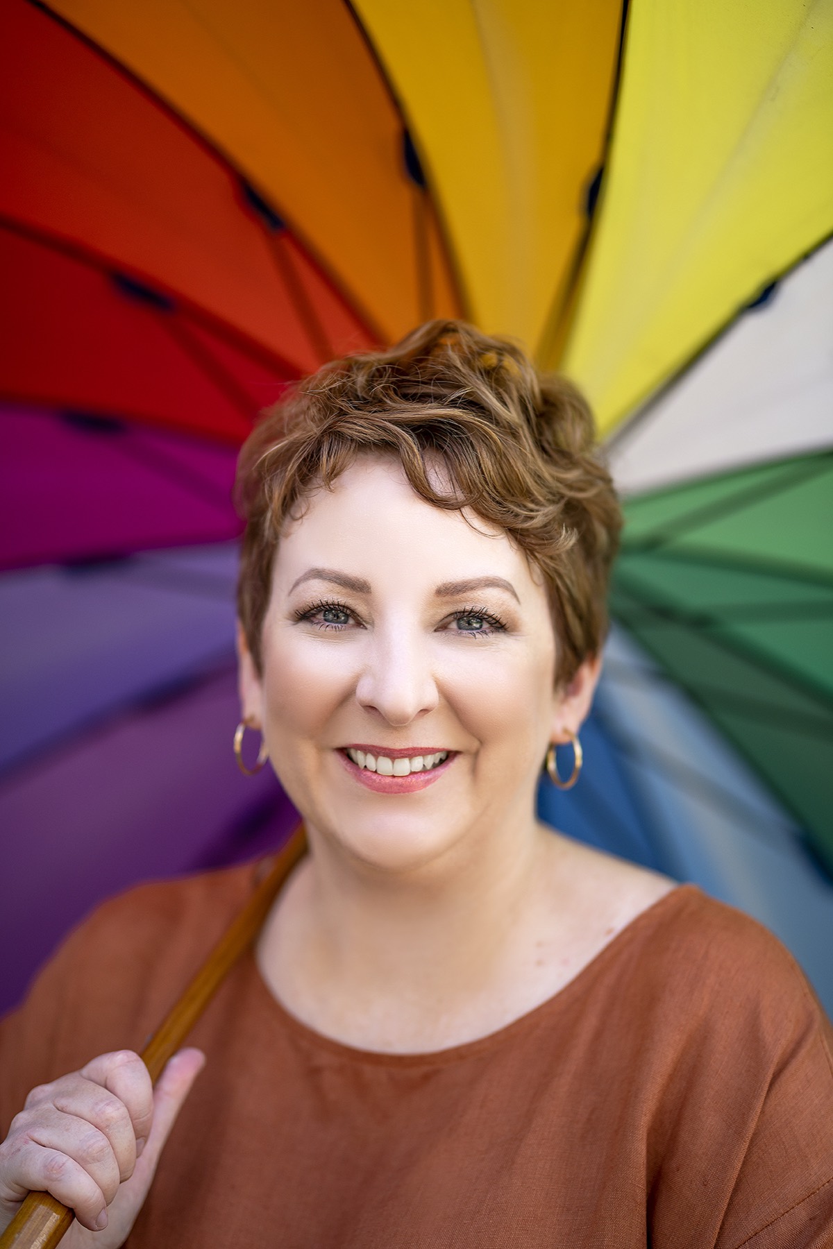 Emma Boddington-Stubbs smiling under a rainbow umbrella